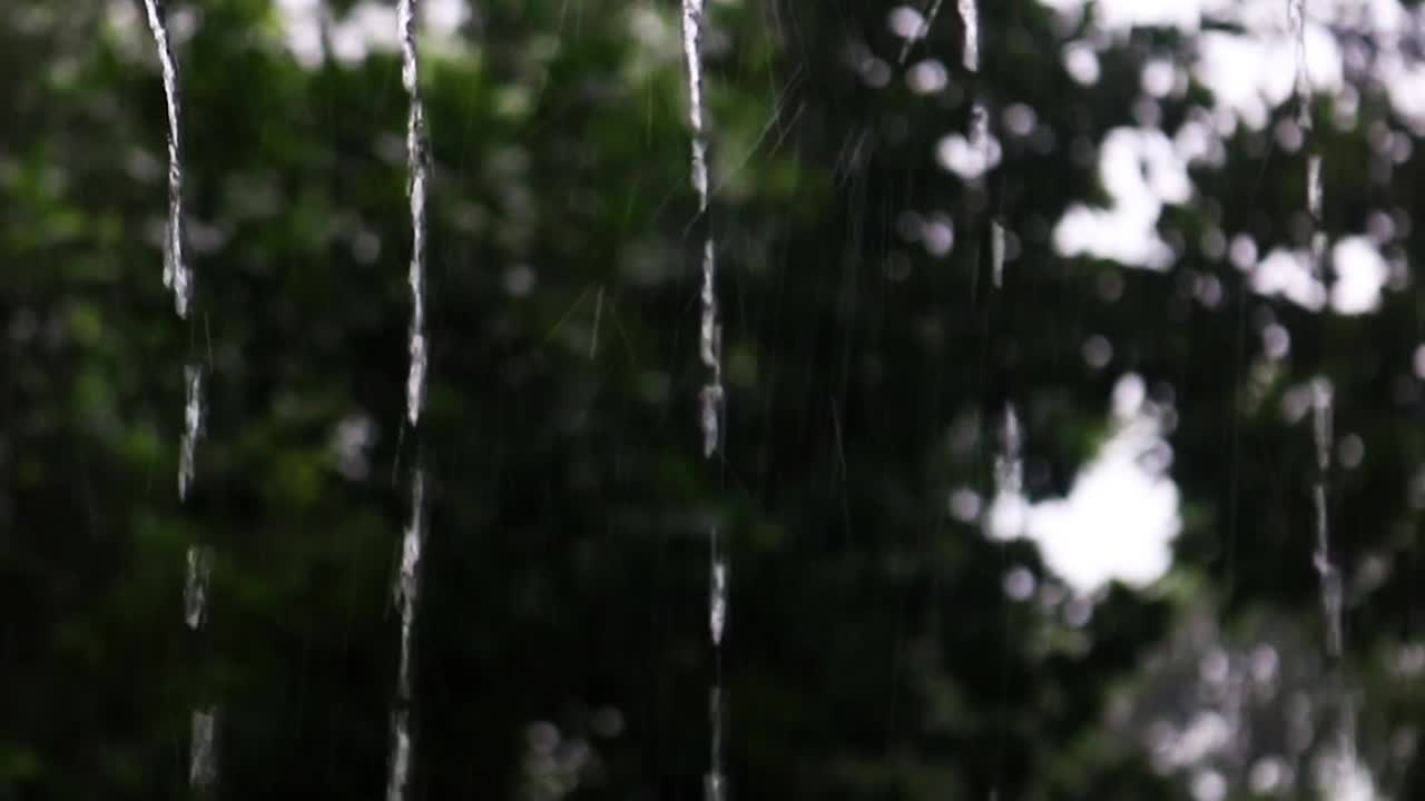 Pouring rainfall from rooftop with beautiful nature background, close up view