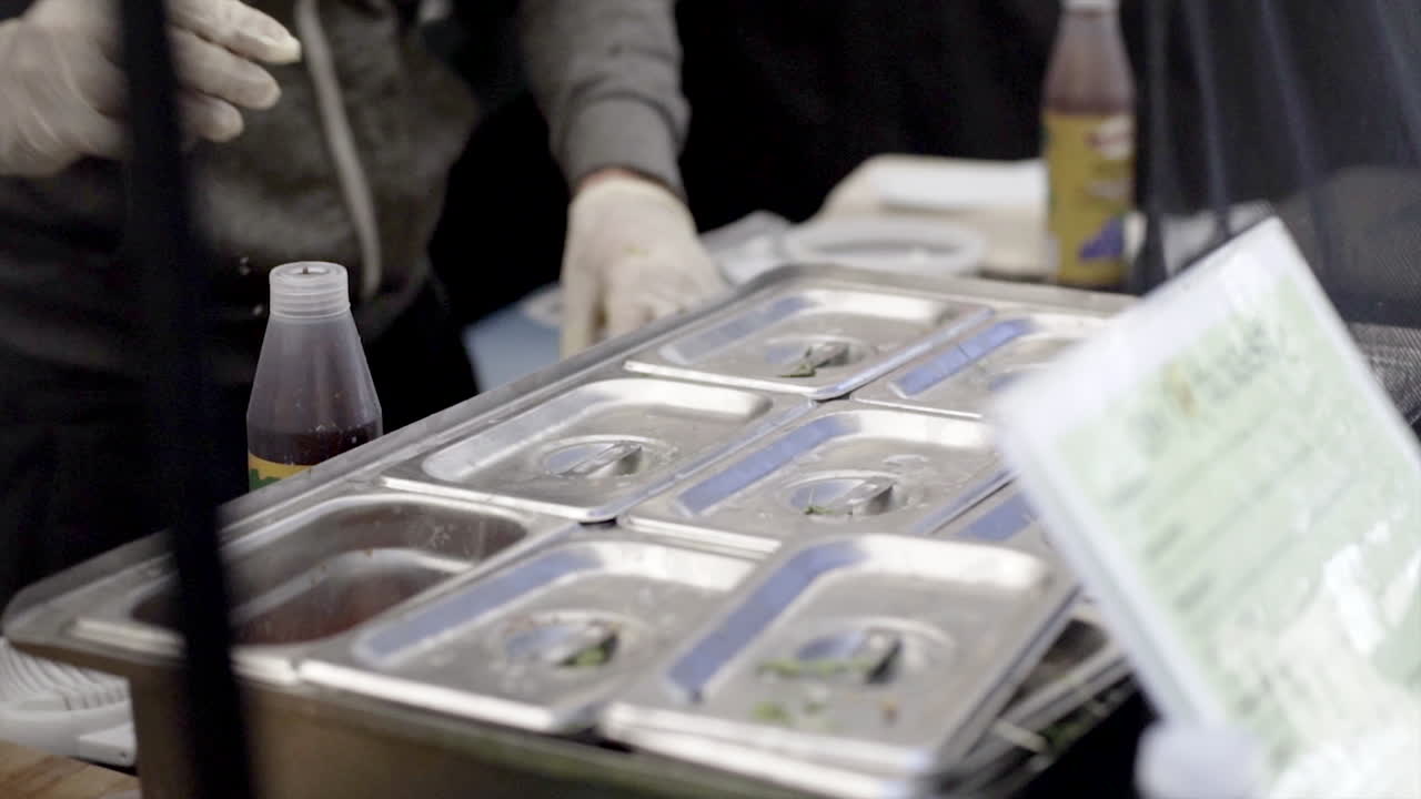 Hands in Gloves Preparing Food at a Food Stall