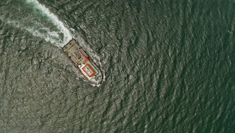 a and orange tugboat sailing through fairly still waters