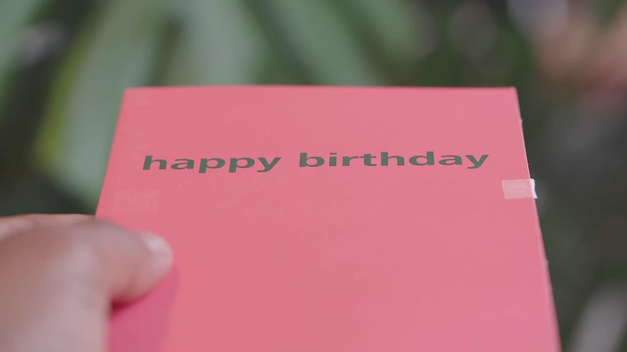 Hand Holding a Pink Happy Birthday Card