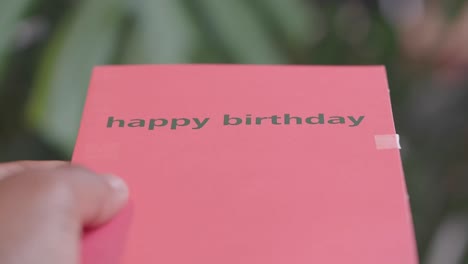hand holding a pink happy birthday card