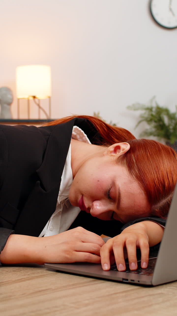 Young businesswoman types report on laptop tired and falls asleep on keyboard exhausted late at work
