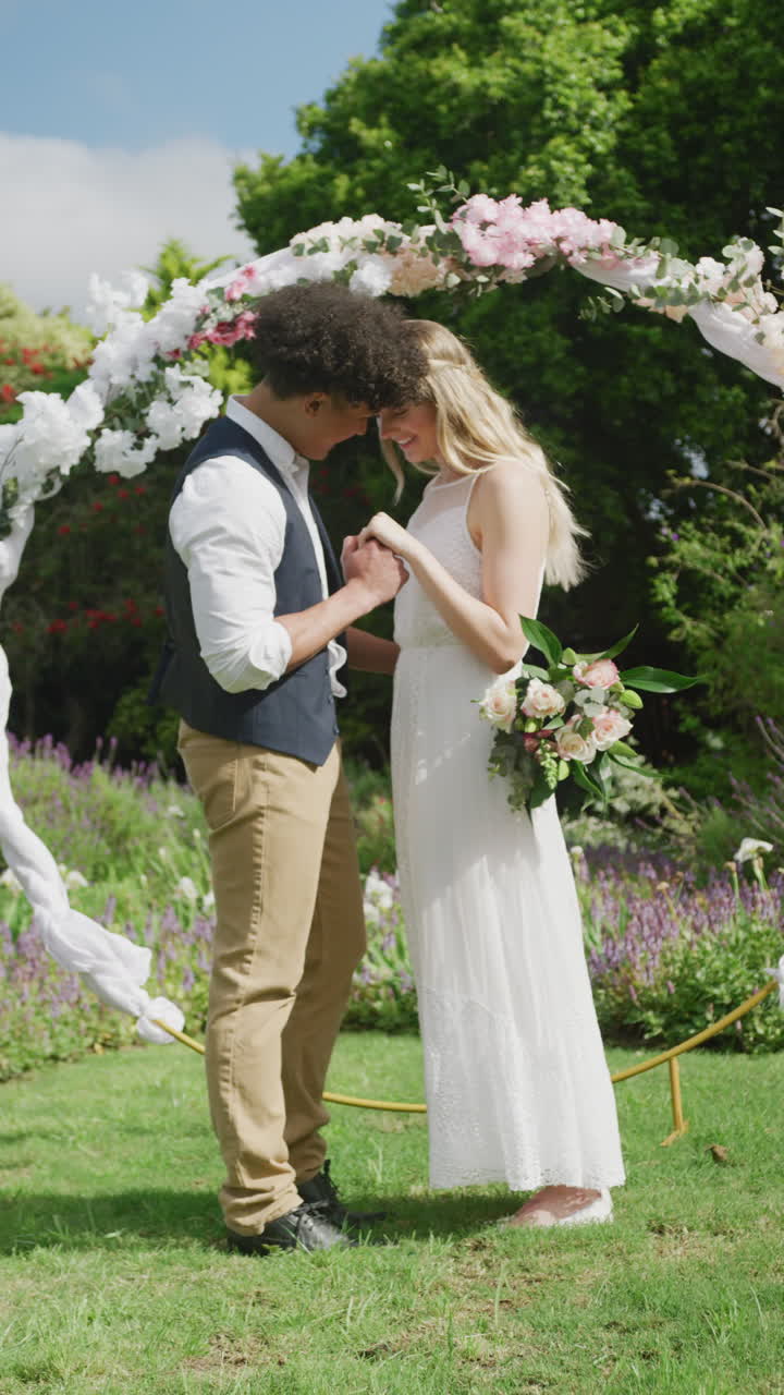 Vertikal video af glad mangfoldigt par i haven på en solrig dag til bryllup.