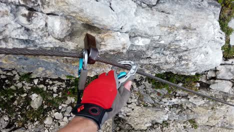 pov of via ferrata climber securing himself by placing the snap links one after another into the next segment