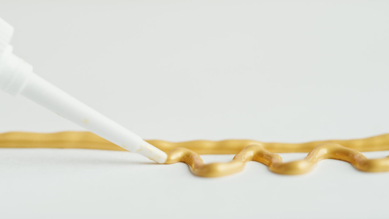 Close-up of Gold Metallic Paint Being Dispensed from a Tube