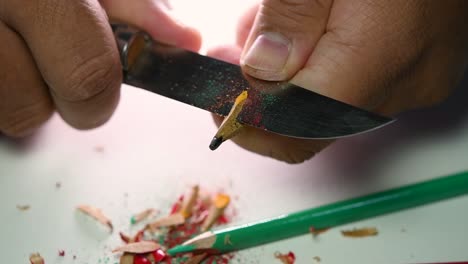 Footage-of-hands-slowly-sharpening-a-pencil-and-some-coloured-pencils-with-a-sharp-knife