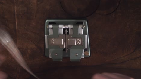 edite con las manos una película de 8 mm en una máquina empalmadora sobre una mesa, por encima de la cabeza