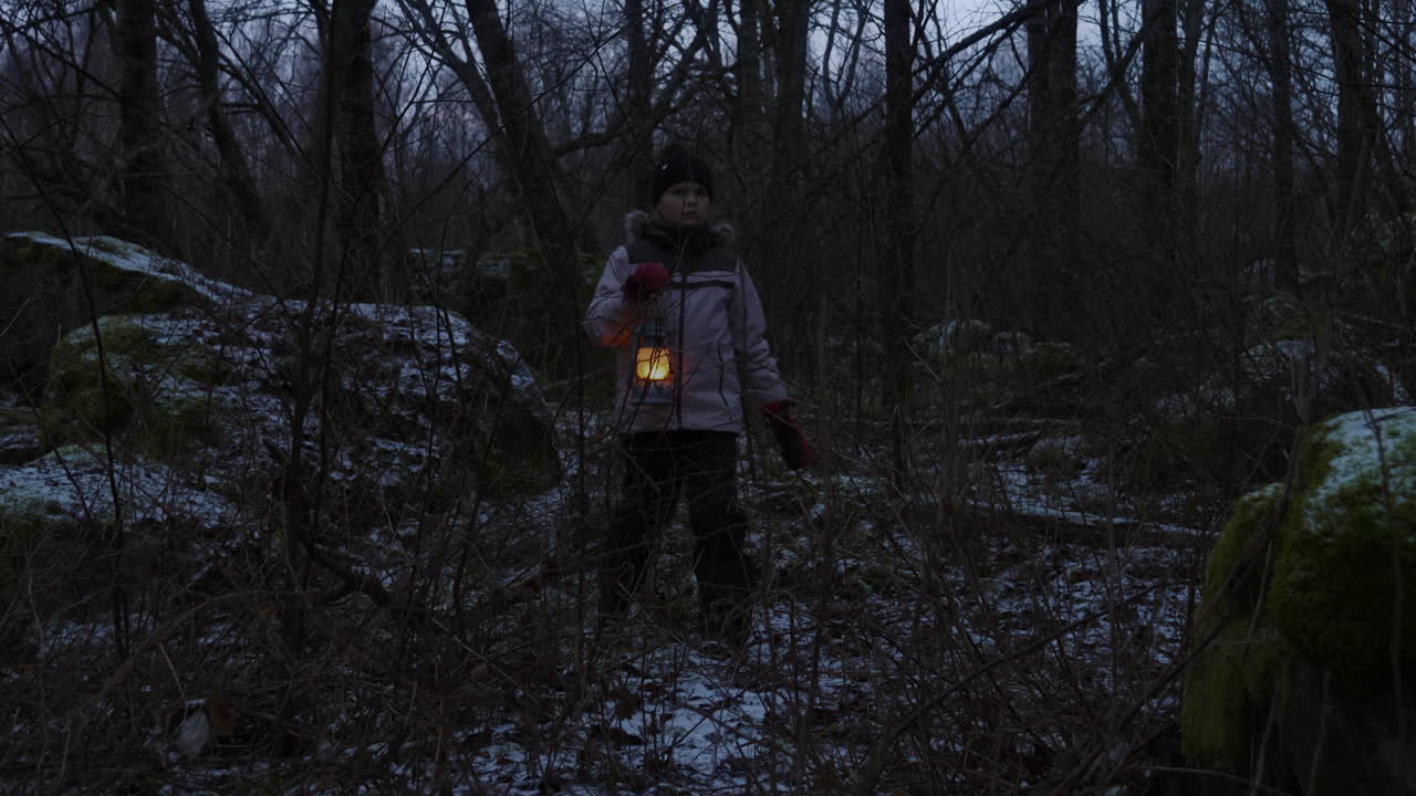 young girl finding her way through the forest with a lantern as the sun sets