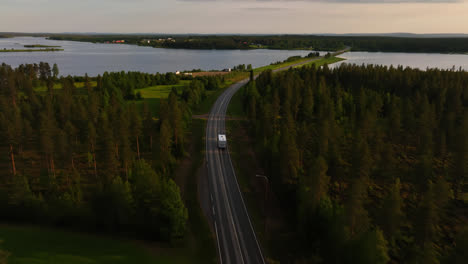 Drone-following-a-RV-passing-lakes-and-the-rural-of-North-Finland,-summer-evening