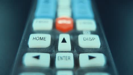 a macro close up slide backwards shot of a black tv remote with white and colorful buttons, studio lighting, slow motion, 120 fps, full hd