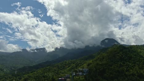 Drone-aerial-shot-of-top-of-the-green-mountain-above-cloudy-sky-near-Puerto-Galera,-Philippines