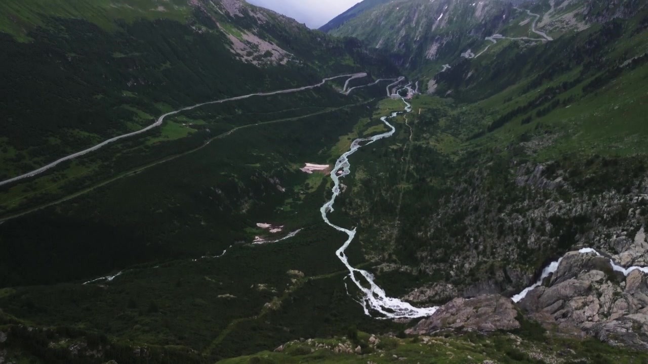 Fosser ved Furkapasset i Sveits på en skyet dag med lite trafikk, filmet med drone