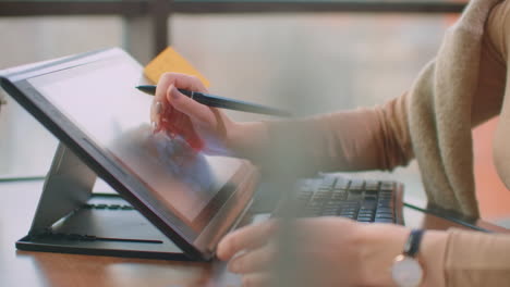 a professional designer in the office draws with a stylus on a graphic tablet sitting in an office with huge windows in the loft style. modern office of graphic designer and creator.