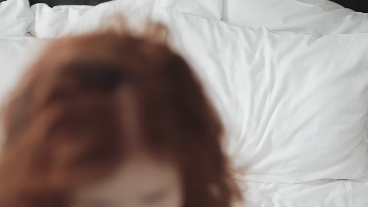 Happy Girl with Red Hair Lying on Bed