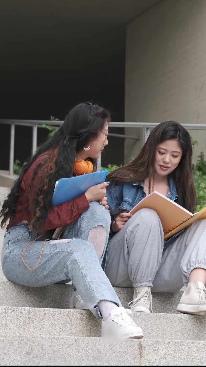 Dos estudiantes asiáticas hablando en el descanso sentadas en el campus