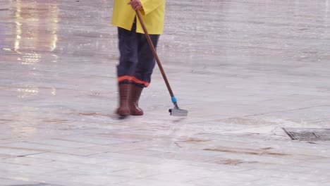 man cleaning the street during rain