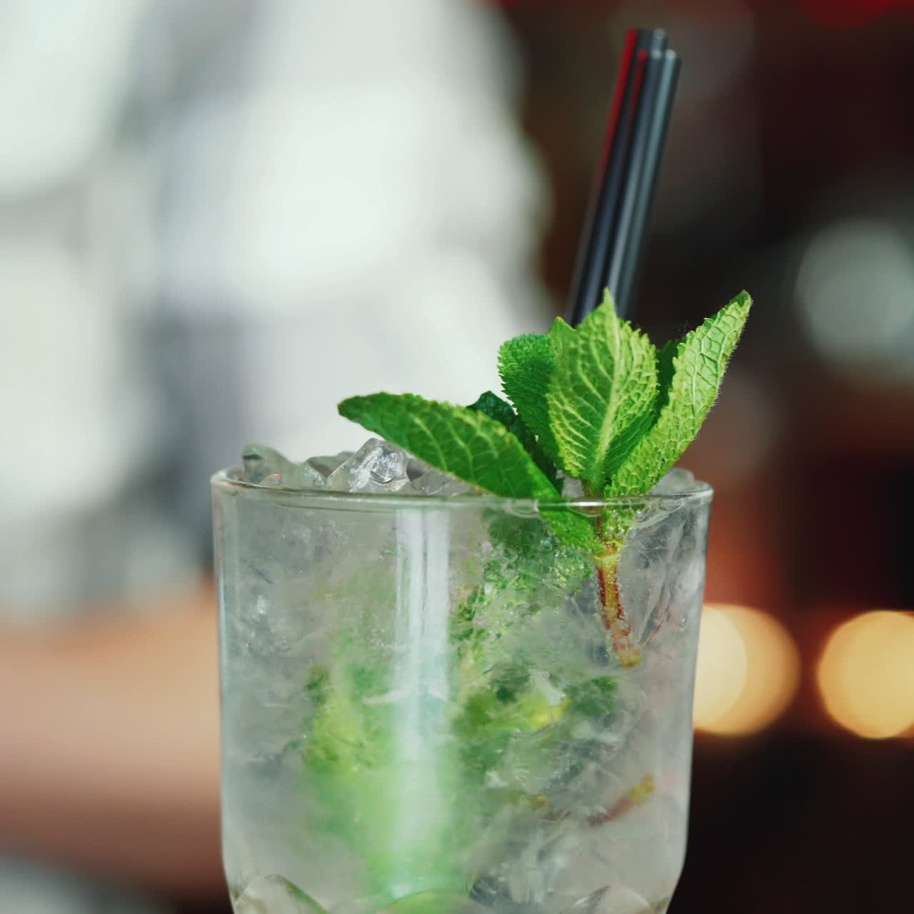 Baarimikko valmistaa Mojito-cocktailia yökerhon baarissa. Ammattimainen moderni baari. Neliövideo