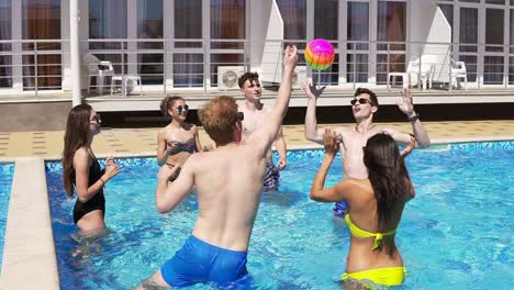 grupo de jóvenes amigos jugando al voleibol en la piscina. fiesta en la piscina de verano. disparo en cámara lenta