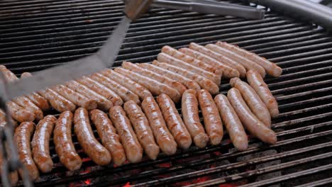 chef grilling fresh meat sausages on big round hanging grill - close up