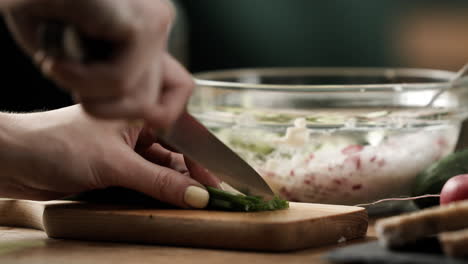 primer plano de cortar cebollino para preparar un sándwich de verduras saludable extendido sobre una colorida mesa de cocina de madera, 4k, 50fps