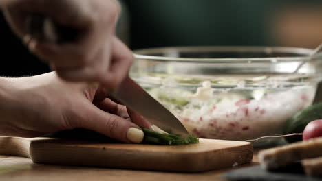 close up of chopping chives to prepare healthy vegetable sandwich spread on colorful wooden kitchen table, 4k, 50fps