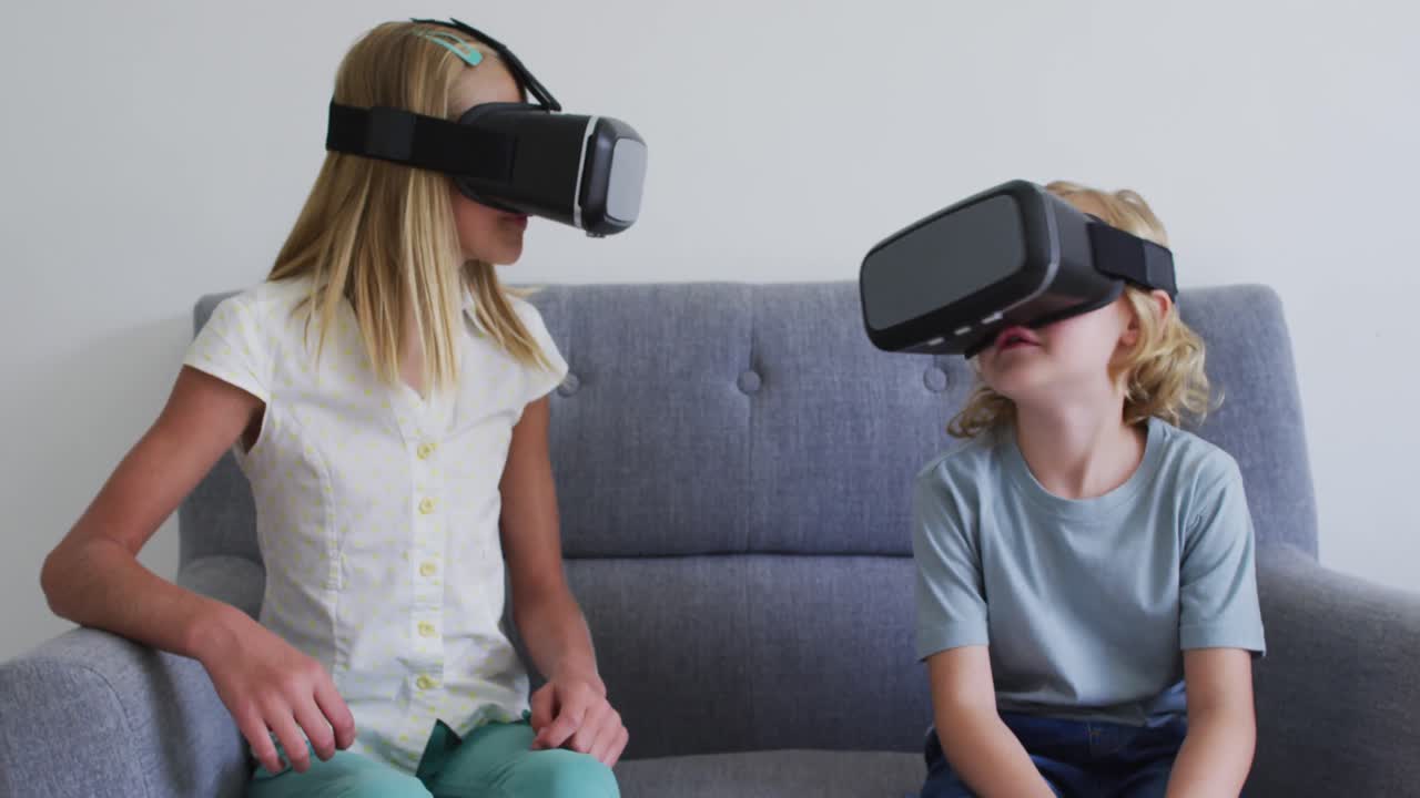 hermano y hermana caucásicos gesticulando mientras usan auriculares vr sentados en el sofá en casa