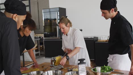 caucasian female chef teaching diverse group preparing dishes and smiling