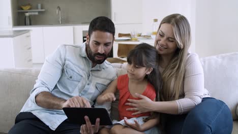 Dad-showing-content-on-tablet-to-excited-little-daughter