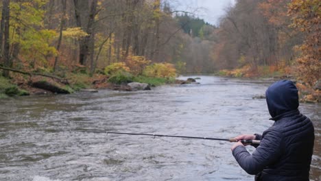 fishing in a mountain river a lone man is fishing in the middle of an autumn landscape fishing in a mountain river a lone man is fishing in the middle of an autumn landscape fast water flow in a river where fish live