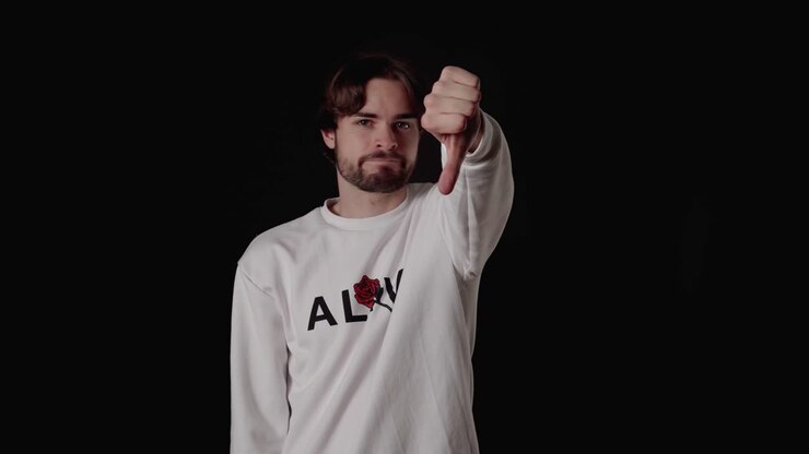 Trendy Young Man giving thumbs down, disapproving gesture, wide, black background
