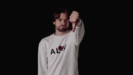 trendy young man giving thumbs down, disapproving gesture, wide, black background