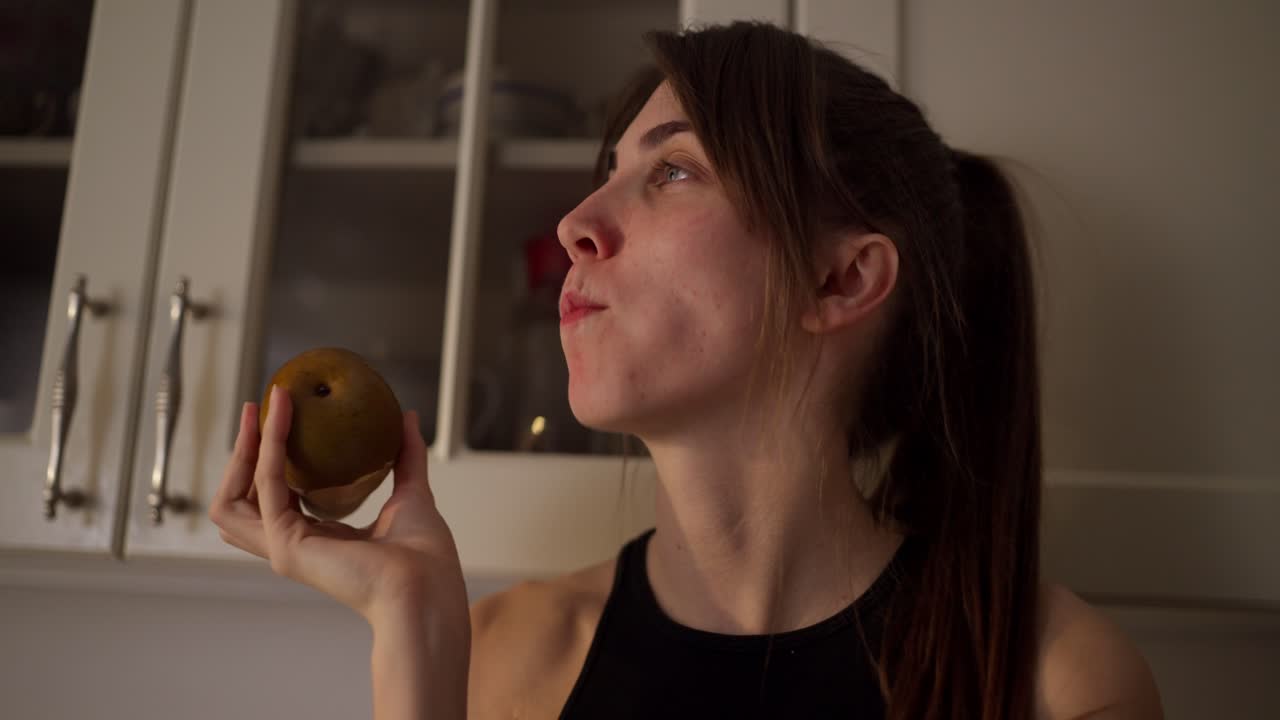 mujer comiendo una pera en la cocina