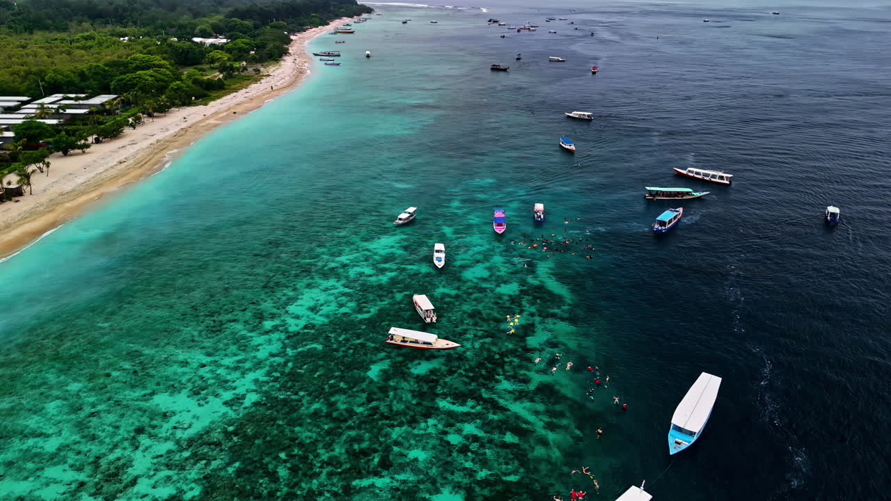 Tourists snorkeling and boats around the Bask Nest underwater sculptures in the stunning turquoise waters - aerial parallax shot