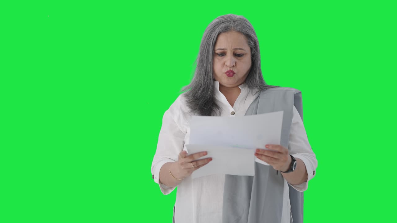 confundida directora india senior leyendo informes de negocios pantalla verde