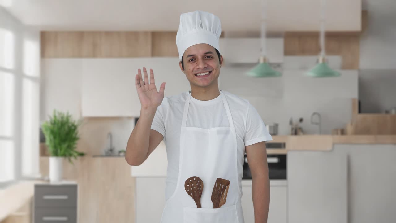 Chef professionista indiano felice che saluta