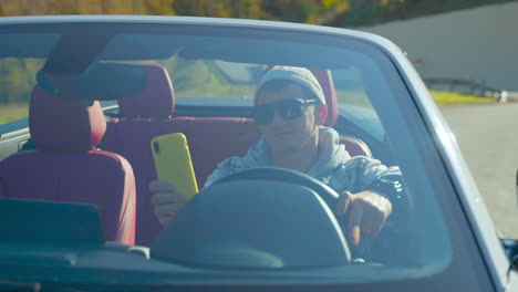 man distracted driving in convertible car