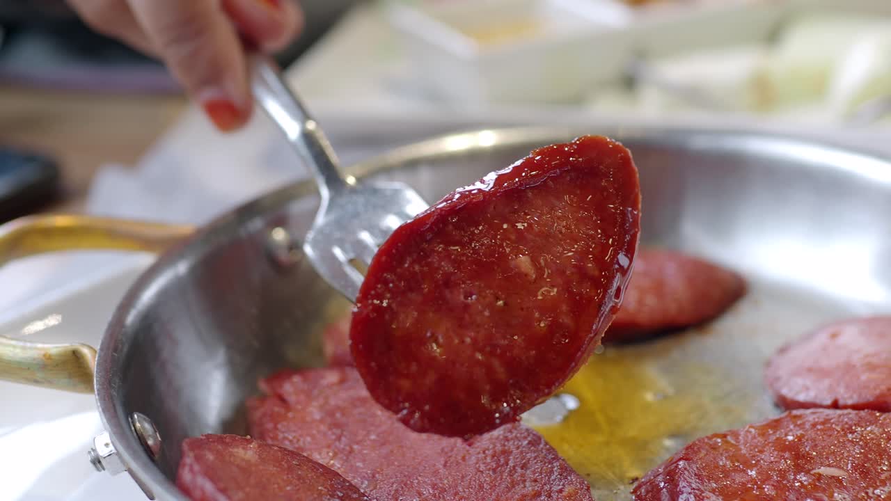 una persona da la vuelta al sucuk en una sartén