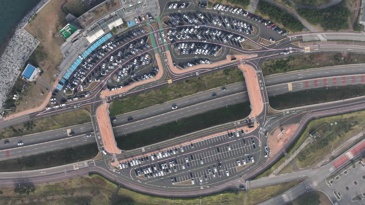 A drone time-lapse of a parking lot full of fun shapes along a highway.