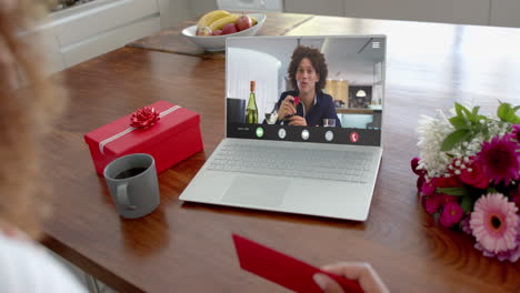 Caucasian-woman-holding-envelope-and-talking-with-biracial-man-on-laptop-screen