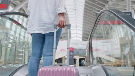 woman with suitcase on an escalator in an airport