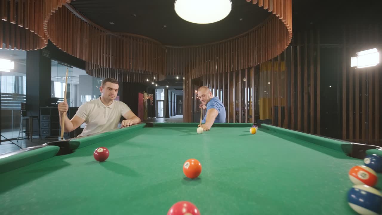 Adult men with disabilities in a wheelchair play billiards in the club