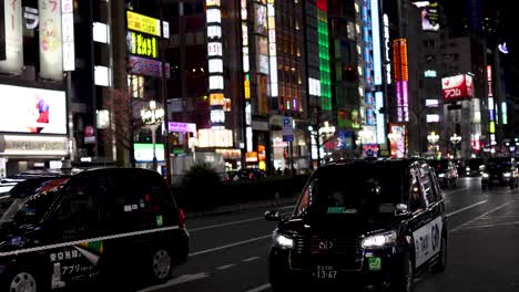 taxis driving through a brightly lit city street