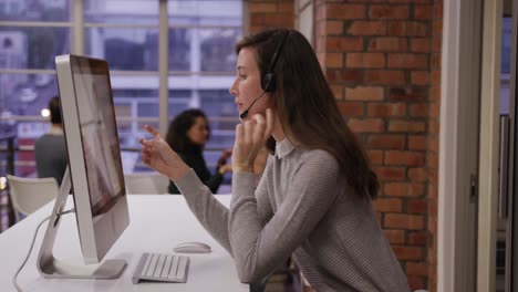 mujer de negocios creativa que usa auriculares hablando en una oficina moderna