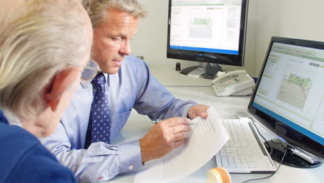 doctor showing senior male patient model of human ear