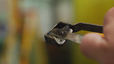 detail of hand of a caucasian male factory worker at a factory using a welding gun striker, sparking