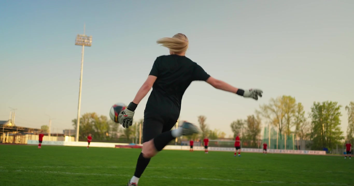 Portiere donna calcia un pallone da calcio su un campo verde durante l'allenamento