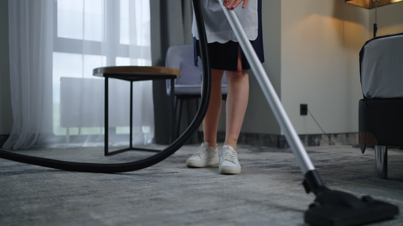 una criada limpia una habitación de hotel con una aspiradora