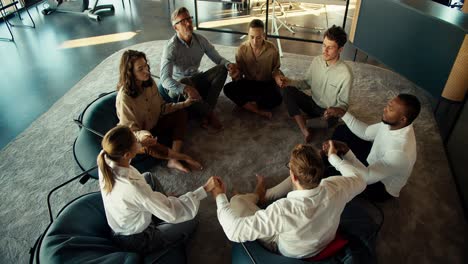 review on group therapy of business people in the office. participants in therapy in business attire sit in a circle and hold hands