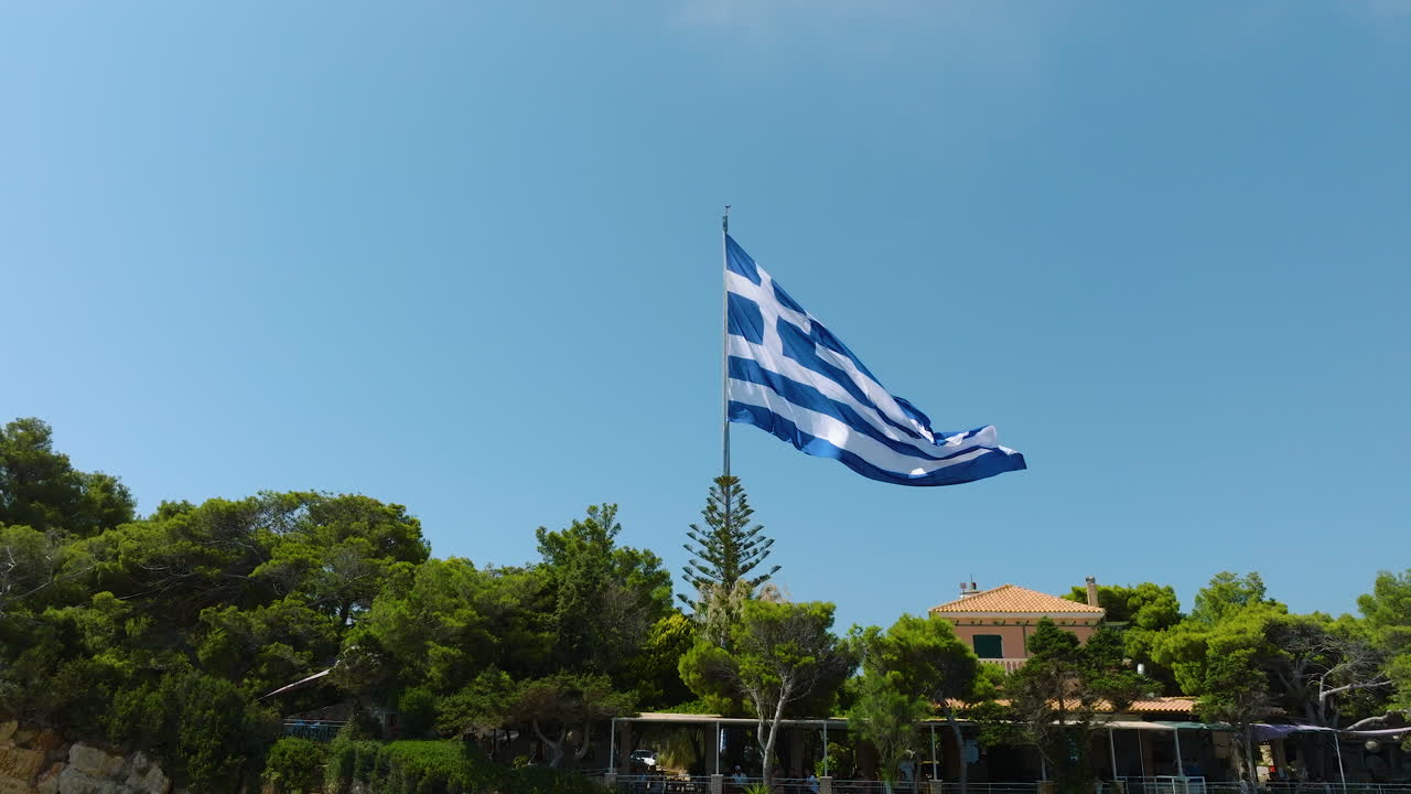 Greek Flag Waving Over Coastal Landscape