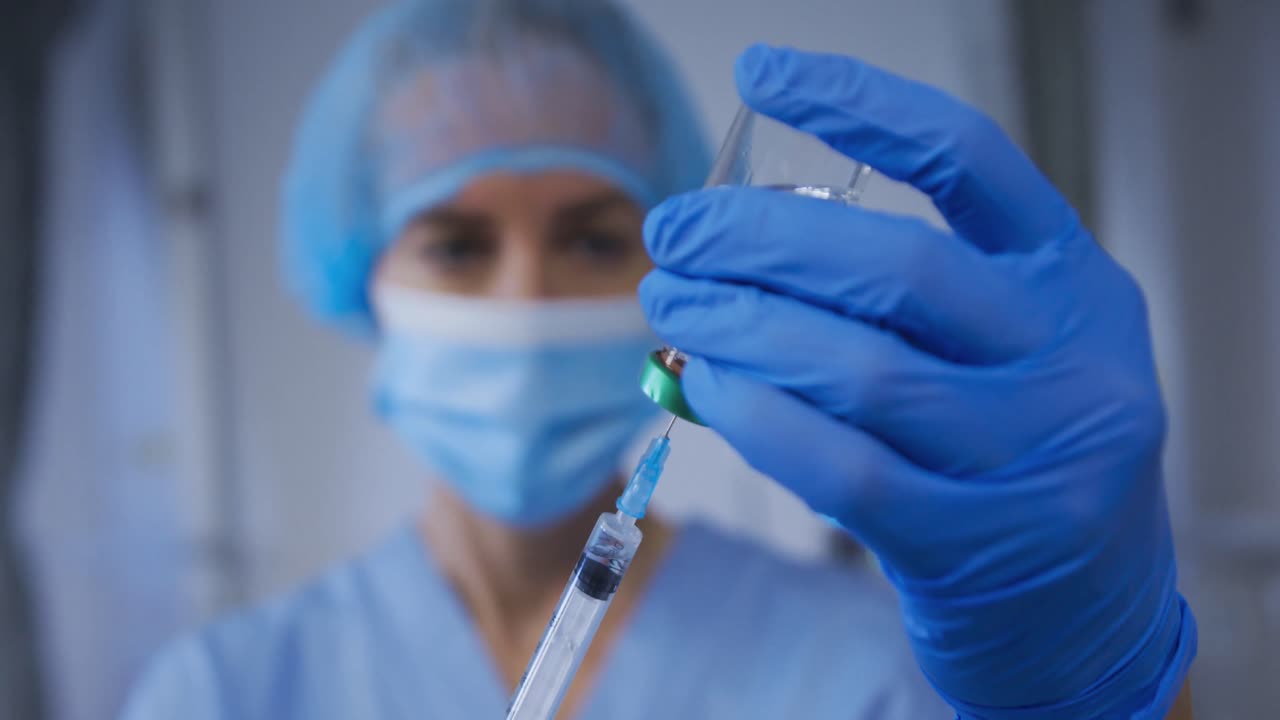 doctora caucásica con máscara preparando la vacuna contra la covid para el paciente